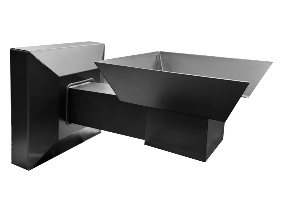 Wall-mounted dual-chute metal hopper for bulk material discharge, industrial equipment style. In/out trays form a two-chute feed system attached to a wall block.